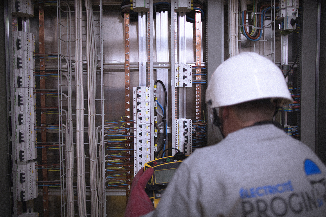 Un électricien de Progin SA effectuant des contrôles électriques dans un tableau sous tension