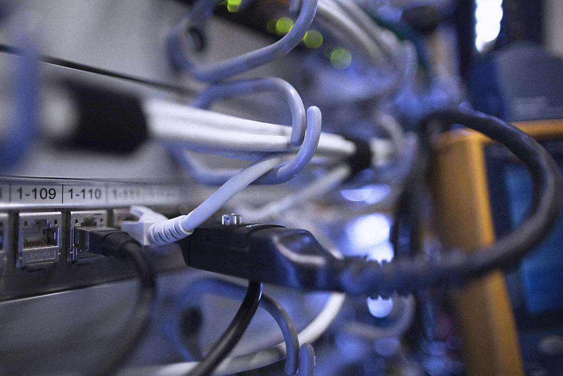 Des câbles réseau Ethernet situés dans un rack informatique et connectés dans une prise de type RJ45